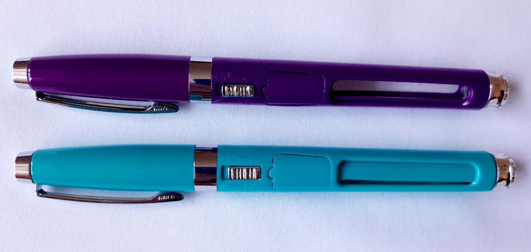 Two pens - one purple and one turquoise, lying on a white surface.